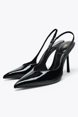 Zapato destalonado acharolado color negro, con tacón fino y punta. Tiene una tira trasera con elástico.