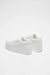 Zapatillas blancas con plataforma gruesa, cordones y puntera redonda.