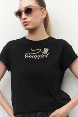 Remera de manga corta de algodón negro con estampa de cowgirl en el centro.