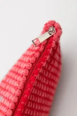 Neceser rojo con textura de tejido de toalla y cierre superior con cremallera.