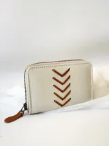 Billetera pequeña de cuero color crudo con cierre metálico y monedero interno. Presenta costuras decorativas en forma de espiga.