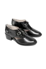 Zapato de cuero negro con textura de piel reptil en la parte trasera y cuero liso en la puntera. Tiene un corte lateral distintivo, cierre con hebilla dorada y tacón cuadrado de altura media.