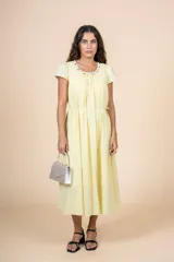 Vestido midi amarillo pálido, de corte recto y manga corta, con escote redondo con detalle de bordado floral. Tiene lazo ajustable en la cintura.