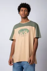 Remera color beige con mangas y parte superior en verde militar. Estampado frontal con texto "Lucky" y diseño de flores con rostro.