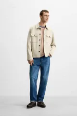 Sobrecamisa color beige de corte recto, con cuello solapa, manga larga con puños abotonados, cierre frontal abotonado, bolsillos de parche con solapa en el pecho y bolsillos de ojal en la cadera.