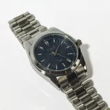 Reloj plateado con correa de eslabones y esfera azul con diseño de ondas.