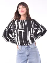 Blusa de mangas largas con cuello redondo y estampado abstracto en blanco y negro.