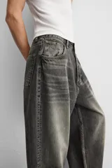 Pantalón de jean negro de corte amplio, con cinco bolsillos, efecto lavado y cierre frontal con cremallera y botón.