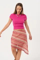 Minifalda roja con estampado de ondas en tonos rosados y beige, con corte irregular y cinturón marrón.