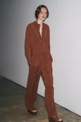 Camisa marrón de Zara Woman Collection confeccionada en hilatura con mezcla de lyocell. Tiene cuello redondo, manga larga acabada en puño, bajo asimétrico con aberturas laterales y cierre frontal con botones.