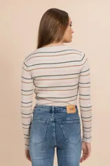Camiseta tejida rib color beige con rayas horizontales en negro, rosa y marrón. Es de manga larga y cuello redondo.