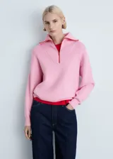 Sweater de punto rosa con cuello alto y cierre de cremallera roja. Diseño recto y manga larga.