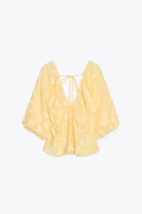 Top amarillo con estampado floral en jacquard, escote en pico, mangas cortas abullonadas con elástico, cintura elástica y espalda descubierta ajustable con lazos.
