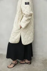 Campera acolchada color beige con patrón de rombos, cuello redondo y cierre con botones a presión.