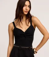 Top cropped blanco de tirantes anchos, confeccionado en tejido de punto texturizado, con escote en V y detalle de nudo o torcido en el centro del busto.