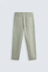 Pantalón color arena de corte recto, confeccionado en tejido de algodón y lino. Cuenta con cintura elástica ajustable con cordón, bolsillos delanteros y traseros de parche.