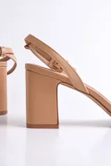 Sandalia de cuero color nude, con tira delgada sobre los dedos, pulsera al tobillo con hebilla y tacón cuadrado.
