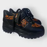 Zapatillas negras con detalles en animal print naranja y cordones negros.