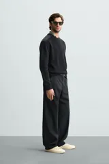 Jersey negro de punto con cuello redondo y manga larga. Presenta parches combinados en hombros y codos.