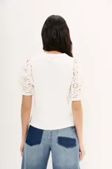 Remera blanca de algodón con calce al cuerpo, cuello redondo y tajos laterales. Mangas balloon con bordado tipo broderie.
