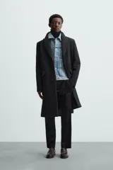 Abrigo negro regular fit confeccionado en paño con lana. Tiene cuello con solapas de muesca, manga larga, bolsillos de solapa en la cadera, bolsillo interior, abertura en el centro de la espalda y cierre frontal con botonadura.