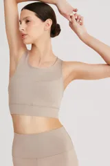 Top deportivo color beige, de cintura ancha y breteles cruzados en la espalda. Confeccionado en tela doble suave y de alta elasticidad.