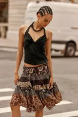 Top negro de seda o satén con escote en V y ribetes de encaje en el borde superior. Presenta un corte halter con tirantes finos que se atan detrás del cuello.