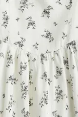 Vestido corto de algodón color blanco con estampado de pequeñas flores negras, escote en V, breteles anchos y falda con vuelo.