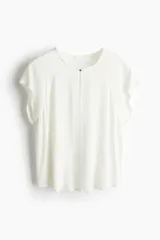 Blusa color blanco hueso de tejido de crepé de viscosa con cuello redondo y abertura de cerradura con botón de metal pequeño adelante. Mangas japonesas de corte raglán y bajo levemente redondeado.