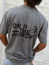 Remera gris con efecto acid wash, corte oversize y cuello redondo. Presenta un pequeño estampado negro con el texto "ON THE MOVE" y un gráfico de damero en el pecho.