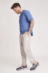 Pantalón de vestir color beige, de corte recto, con bolsillos laterales y traseros. Se ajusta a la cintura con cinturón de cuero marrón.