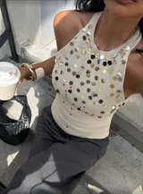 Top blanco de tejido de punto con cuello halter y espalda descubierta. Decorado con apliques de lentejuelas plateadas y doradas.