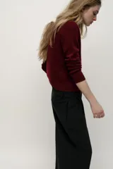 Chaqueta de punto liso color rojo, confeccionada en 100% lana. Tiene cuello redondo, manga larga, terminaciones en rib y cierre frontal con botones.
