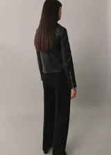 Chaqueta de cuero ovino negra, estilo biker, con cuello con solapa, cierre frontal asimétrico con cremallera, dos bolsillos laterales con cremallera, mangas largas con cremallera en los puños y forro interior de poliéster.