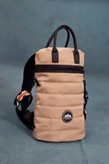 Matera estilo mochila color beige, confeccionada en nylon combinado con símil cuero. Tiene tapa con cierre metálico, bolsillo interno, asas cortas y correa extensible.