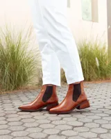 Botas estilo Chelsea de cuero vacuno color marrón con textura grabada tipo reptil. Presentan paneles elásticos laterales en color negro, puntera almendrada y taco cuadrado de madera.