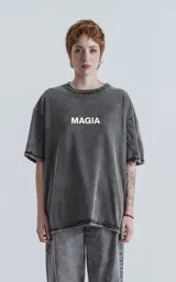 Remera manga corta gris con efecto nevado, cuello redondo y calce oversize. Estampa frontal con la palabra 'MAGIA' en color gris claro.