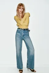 Jeans de tiro alto color azul claro, con cinco bolsillos y pernera recta que se estrecha hacia el tobillo. Incluye un cinturón negro con detalles metálicos.