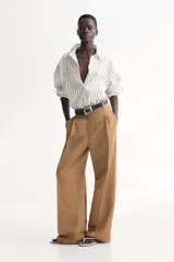 Pantalón de vestir color camel, de corte amplio, tiro alto y largo hasta el tobillo.