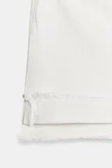 Shorts de jean de algodón, tiro alto, color azul claro desgastado. Presenta cinco bolsillos, cierre frontal con botón metálico y bajo desflecado con vuelta.