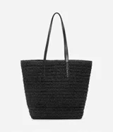 Bolso de playa negro tejido en paja de papel, con asas de hombro en cuero sintético y detalle de borla colgante.