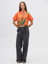 Camisa crop verde con estampado abstracto en tonos naranja y celeste, de mangas cortas y cuello camisero. Confeccionada en viscosa.