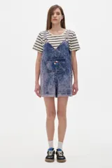 Mono enterito corto de denim con lavado gastado, corte oversized y tirantes regulables.