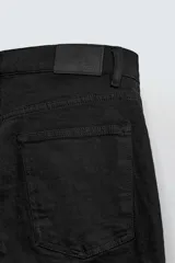 Pantalón de jean negro, corte slim fit, con tiro medio, cinco bolsillos, efecto lavado y cierre frontal con cremallera y botón.