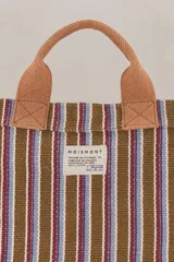Mini bolso tote de algodón a rayas verticales marrones, azules y blancas, con doble asa de mano marrón y correa de hombro ajustable marrón.