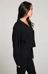 Campera negra de tejido de punto con ajuste holgado, cuello de banda, cierre frontal con cremallera y mangas cortadas al bies.