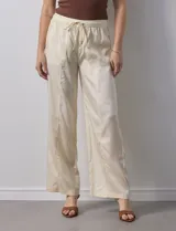 Pantalón palazzo color crema, marca Nanette, con pretina elastizada, lazo de ajuste y bolsillos delanteros.