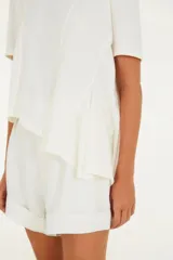 Remera blanca de corte amplio con cuello redondo, manga corta y detalles de costuras en el frente.