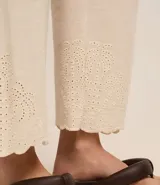 Pantalón recto de cintura alta confeccionado en viscolino color crudo, con elástico en la parte trasera de la cintura, cierre tradicional y textura de palmeras perforadas en el bajo.
