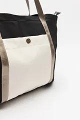 Bolso tipo tote de nylon color negro con bolsillo frontal blanco y asas largas color beige.